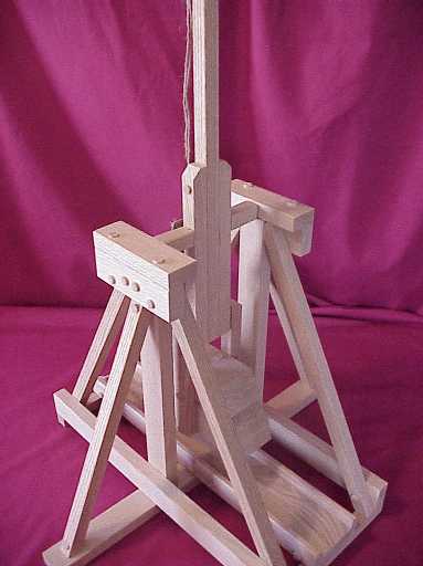 Front view of a working scale model trebuchet in the fired positon showing the trestles and throwing arm.