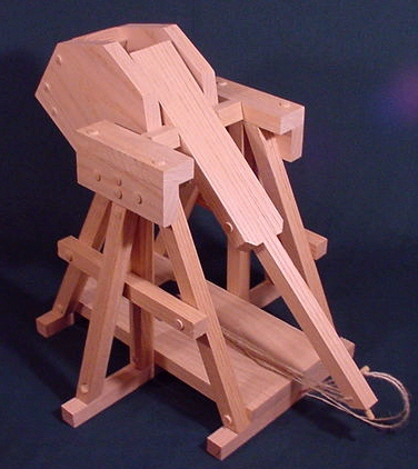 Back view of a wood working model of a trebuchet in the cocked position showing the sling and release pin