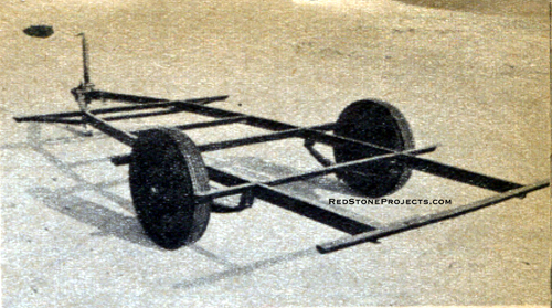 Photo of the steel chassis of a canned ham trailer showing spares, crossmembers amd wheel and tires.