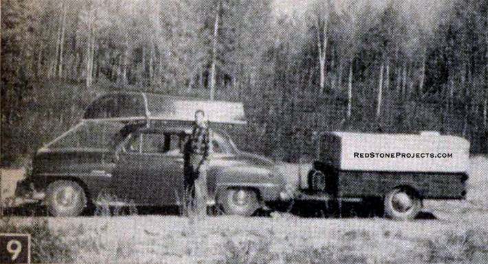 Vintage photo of a hunter beside his auto and camping trailer.
