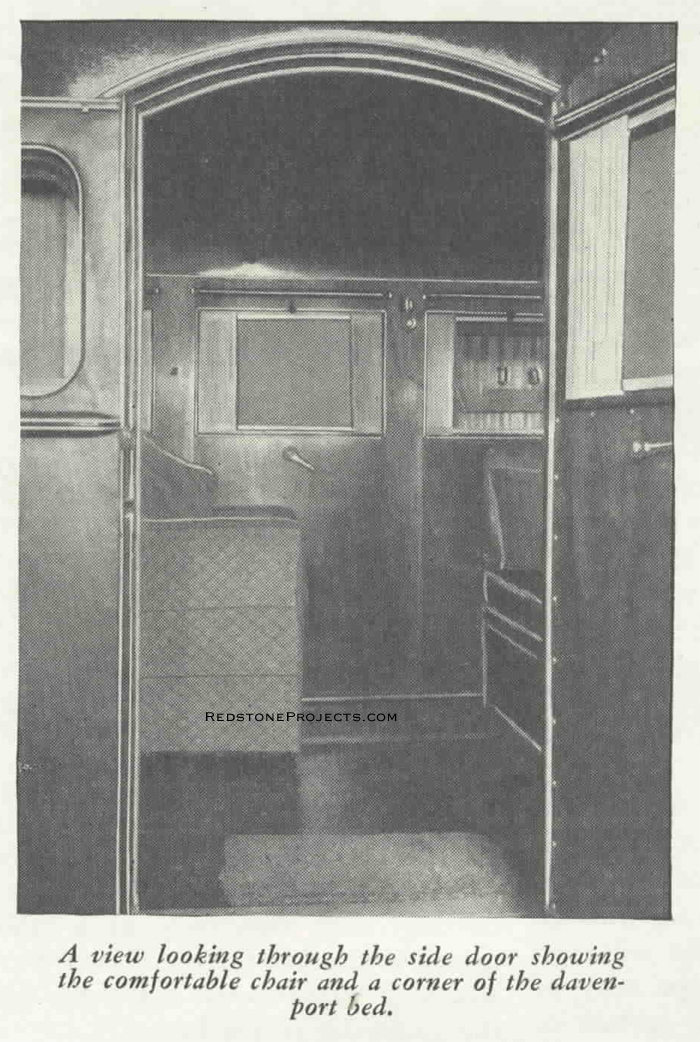 A view looking through the trailer door showing the comfortable chair and a corner of the Davenport bed.