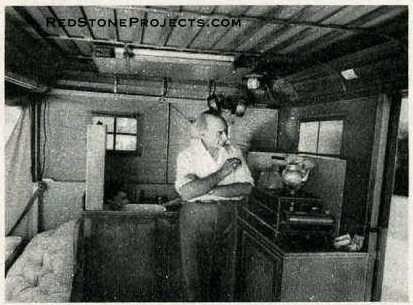 Here is the trim interior of Sir Guy Standing’s trailer. On the sink at the left is the portable water tank. Note folding table strapped to the roof. Pipes supporting roof and strengthening guy wires can be seen in rear.