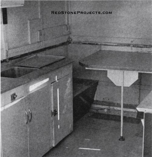 For eating purposes, the table is raised to its proper level. The cupboard with sink is fitted with a water pump and icebox, at right under the sink, can be reached when trailer is closed.