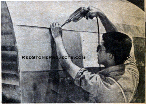 Photo of a man installing the aluminum skin on the rear of a canned ham trailer.