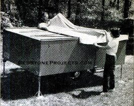 When setting up the trailer, place the stabilizing jacks at each corner first. Next, remove the tarp, install the supporting arms for the bunk panels and swing the latter into place. Then erect the folding top, secure it to the snaps, and finally erect the door-and-frame unit and snap the canvas top to it.