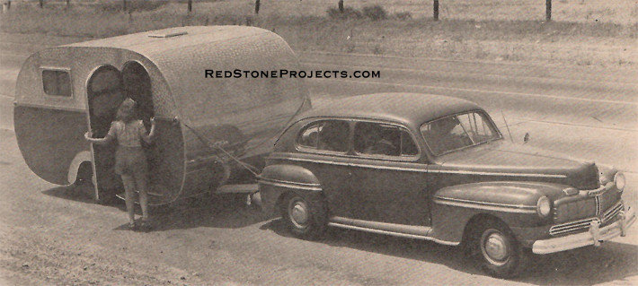 Picture of a lady opening the door of a wanderer trailer tha is hithced to a 1940's sedan.