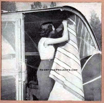 Woman installing the side fabric panels on an open Wild Goose Kamp Master camping trailer.